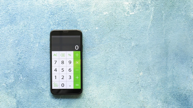 Celular com a tela ligada em uma calculadora para representar aplicativos de controle de finanças.