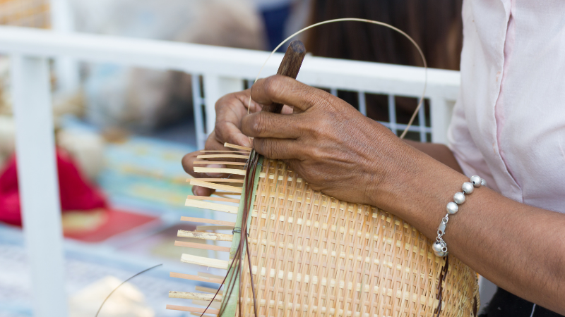 Artesão manuseando um cesto de bambu trançado.