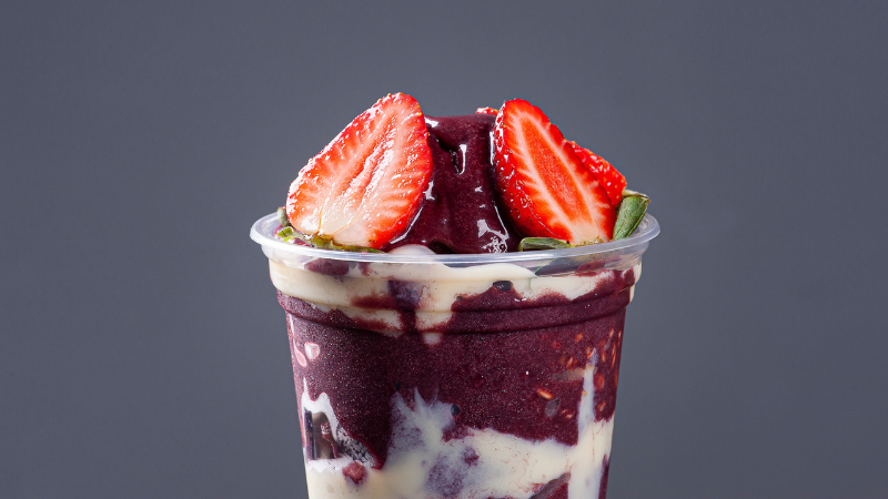 Copo montado de açaí com morango e leite em pó.